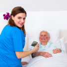 elder woman in bed with caregiver beside her