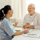 caregiver with elder man drinking coffee