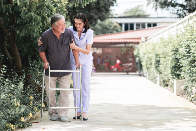 Nurse with patient using walker in retirement home. 