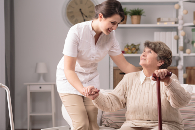 young carer supporting senior woman with walking stick