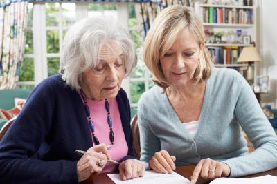 female ceregiver helps senior woman to complete form